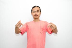 Asian, Indonesian man standing wearing pink shirt pointing right, left, up, down and presenting using hand gestures. Isolated on white background photo