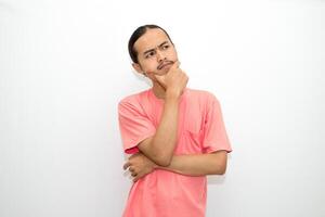 Asian, Indonesian man standing with his hand on his chin and head as if in deep thought, thinking about work or schoolwork. Isolated on white background photo
