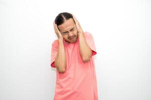 An Indonesian, Asian man wearing a pink tshirt having a headache, chest pain and stomach ache with hands holding head, chest and stomach. isolated in white background photo