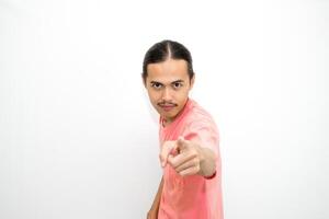 An Indonesian, Asian man wearing a pink tshirt shows a fierce expression as if he is angry or frustrated. isolated in white background photo