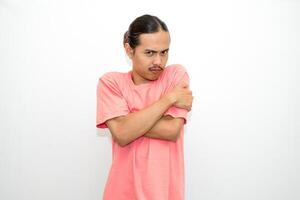An Indonesian, Asian man wearing a pink tshirt shows a fierce expression as if he is angry or frustrated. isolated in white background photo