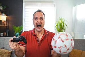 Middle age Caucasian man playing soccer game at home photo