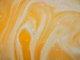 High-angle full-frame shot of coffee and milk swirling together, featuring frothy foam bubbles and creating a captivating abstract pattern. photo