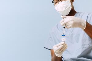 Unrecognizable person holding an injection and a dose. Gloved hands holding corona virus vaccine. photo