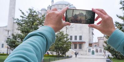 A male tourist takes a photo of the Fatih Mosque in Istanbul, Turkey as a keepsake.