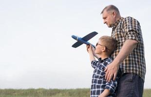 Father and son having fun in the field playing with an airplane photo