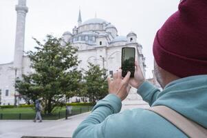 A male tourist takes a photo of the Fatih Mosque in Istanbul, Turkey as a keepsake.