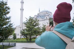 A male tourist takes a photo of the Fatih Mosque in Istanbul, Turkey as a keepsake.