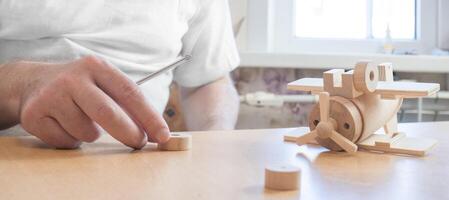 Happy father's day and childhood concept. Close-up of a father and a boy son in glasses work with hand tools, using a screwdriver, assembling a wooden house constructor at the table. photo