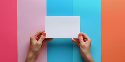 Hand holding a blank white box on colorful paper background during creative workspace setup photo