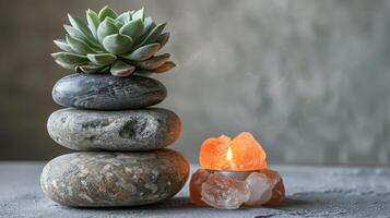 A tranquil arrangement of stones, a succulent, and a glowing candle on a serene surface photo