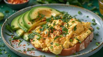 Delicious breakfast toast topped with avocado, scrambled eggs, and spinach on a green plate photo