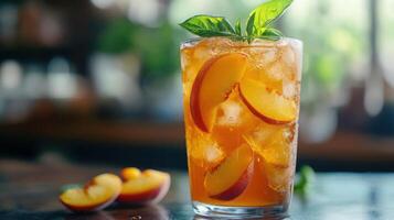 A refreshing peach tea is served in a clear glass with ice cubes, photo