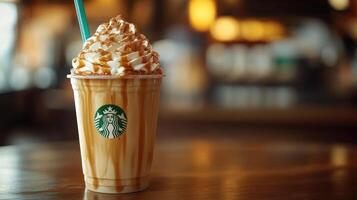 Starbucks foam latte with caramel drizzle and whipped cream, sitting on a wooden table at a cafe. photo