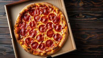 Freshly baked pepperoni pizza with sliced peppers in a delivery box on a wooden table photo
