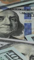 A collection of hundred dollar bills is shown, featuring the intricate design details and the familiar portrait of Benjamin Franklin. The banknotes display various aspects of their physicality. video
