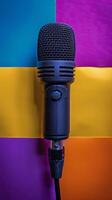 A close up view of a black microphone against a colorful background of purple and yellow hues photo