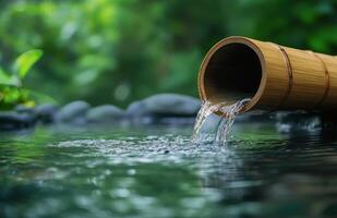 Bamboo water feature gently flowing into a serene pond surrounded by lush greenery photo