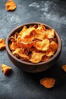 Brightly colored dried chanterelle mushrooms in a wooden bowl on a dark surface photo