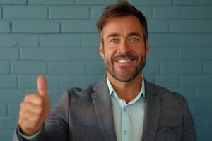 Young man smiling and giving thumbs up against a vibrant blue background indoors photo