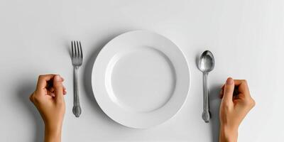 Hands poised to eat at a dining table set with a plate, fork, and spoon ready for a meal photo