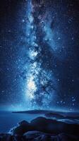 Starlit night over a calm sea reflecting the Milky Way in clear twilight skies photo