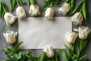 White tulips arranged around a blank card on a wooden table for personal messages and notes photo