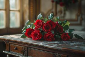 A bouquet of red roses arranged elegantly on a vintage wooden table near a sunlit window photo