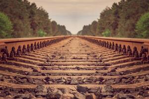 Rails and sleepers extending into the distance. Infinity effect. Against the background are green trees. Infinity and loneliness. Railway transport. photo