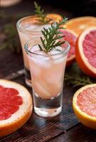 Alcoholic cocktail with grapefruit and citrus, ice and juice, drink glass on a wooden board, old rustic style, selective focus photo