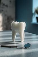 Large dental tooth model with a dental mirror on a blue table in a well lit room photo