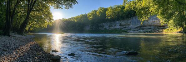 Morning sunlight filters through trees over tranquil river at dawn in rural landscape photo
