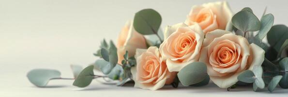 Delicate arrangement of light peach and cream roses with green eucalyptus leaves on a wooden surface photo