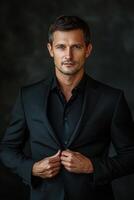 Confident man adjusting his blazer in a sophisticated pose against a dark background photo