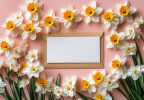 Bright white card surrounded by daffodils on a pink background during springtime photo