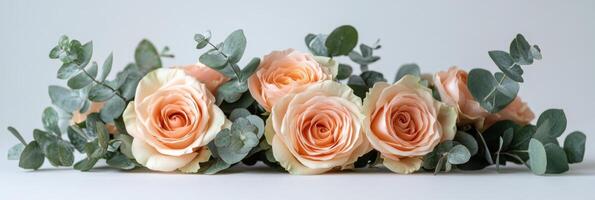 Delicate arrangement of light peach and cream roses with green eucalyptus leaves on a wooden surface photo