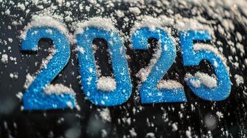 Snow covered numbers 2025 on a black surface during winter with falling snowflakes in the background photo