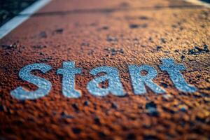 Close up of a weathered track start line marked on a red surface during early morning light photo