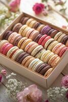 Colorful macarons arranged in a decorative box with flowers on a rustic wooden table photo