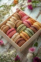 Colorful macarons arranged in a decorative box with flowers on a rustic wooden table photo