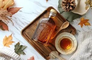 A warm autumn setup featuring a bottle of syrup, a cup of tea, and colorful leaves on a table photo