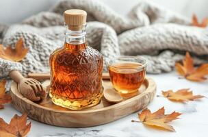 A warm autumn setup featuring a bottle of syrup, a cup of tea, and colorful leaves on a table photo