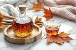 A warm autumn setup featuring a bottle of syrup, a cup of tea, and colorful leaves on a table photo