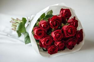 Beautiful bouquet of red roses tied with a white ribbon on a soft gray background photo