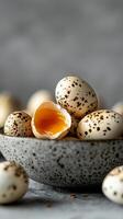Quail eggs in a speckled bowl with one cracked revealing bright yolk, captured in a kitchen setting photo