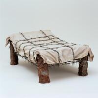 Barbed wire wrapped in tattered cloth on a rusty metal frame photo