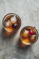 Two refreshing cocktails with cherries served on ice in stylish glasses on a marble surface photo