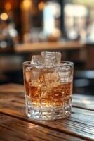 A glass filled with ice cubes on a wooden table illuminated by warm sunlight in the afternoon photo