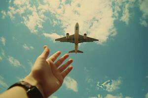 A person reaching out as an airplane soars above bare trees in a clear blue sky photo