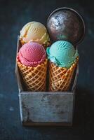 Three colorful ice cream cones displayed in a vintage wooden box on a dark surface photo